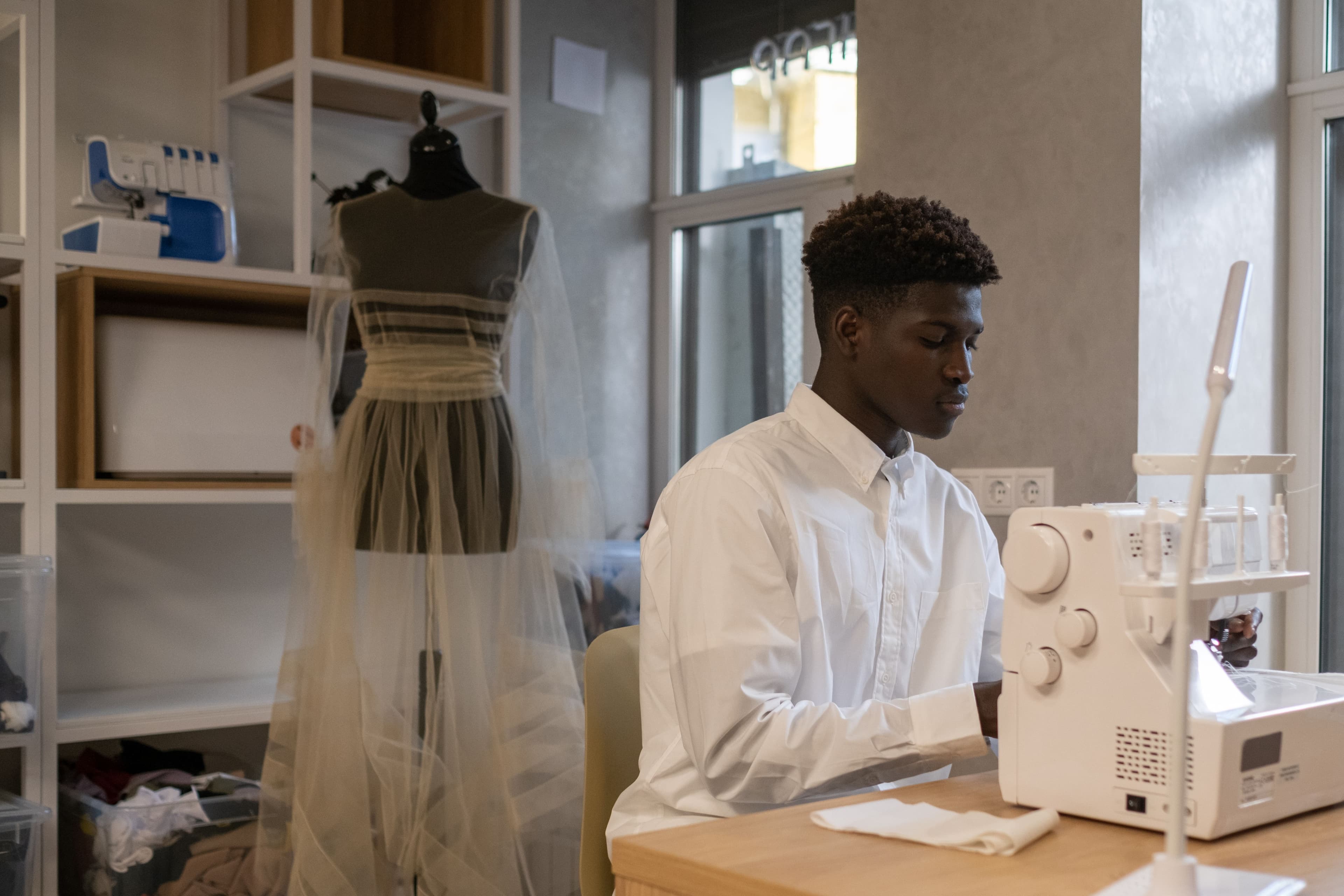 Couturier à la machine dans l'atelier, mannequin et tulle au second plan